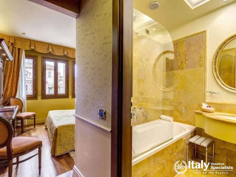 A peek into a luxury bathroom reveals the marble touches of a suite at Hotel Al Codega.