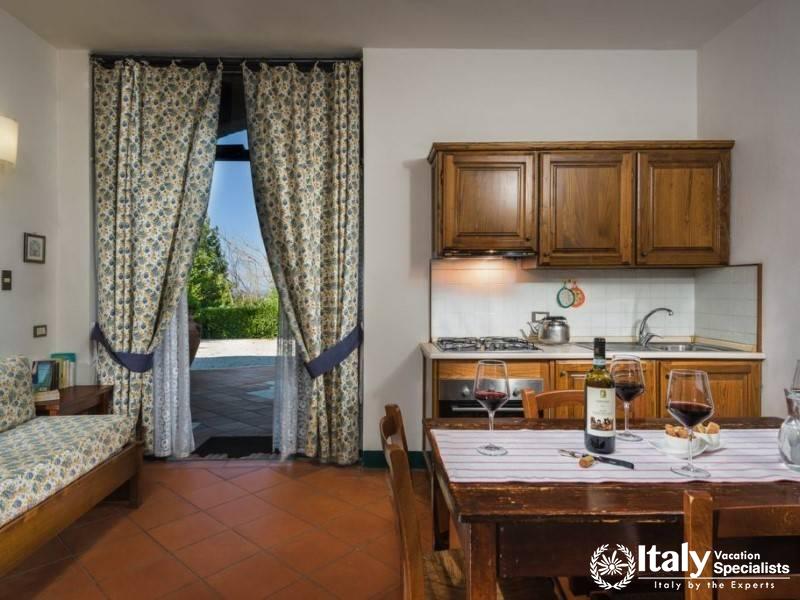 Bright and airy studio room opening onto a patio, with kitchen and dining space close by.