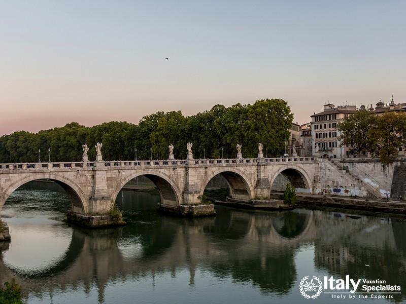 Ancient bridge in Rome with statues reflecting in the water
